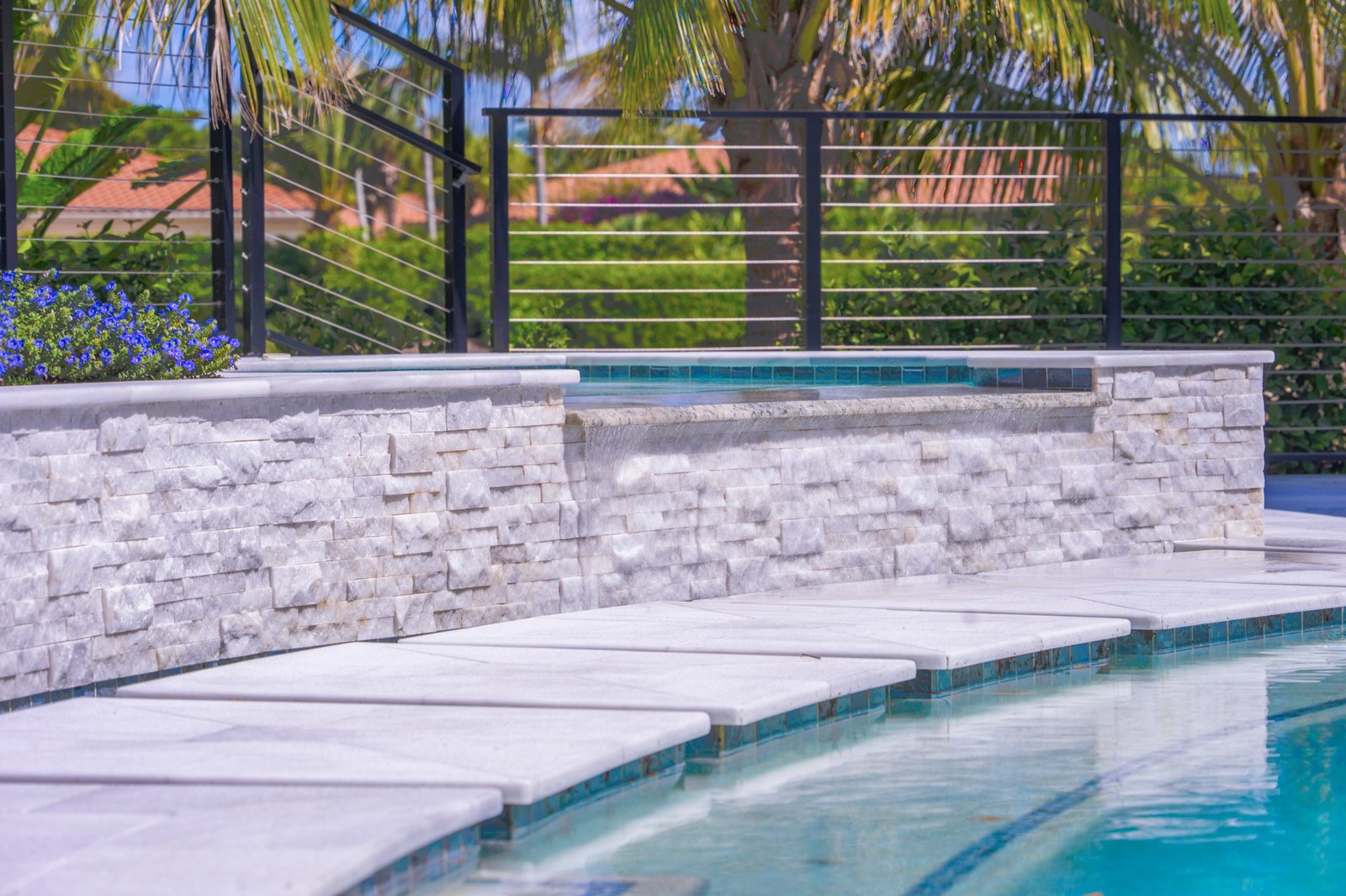 Stone wall and water feature detail beside a pool